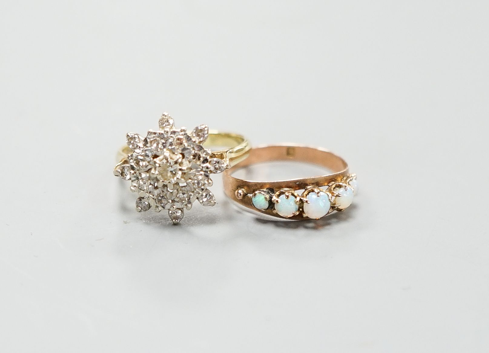 A yellow metal (stamped 9) and graduated five stone white opal set half hoop ring, size M, gross 1.2 grams and and 18ct gold and diamond chip cluster ring, gross 4.6 grams.